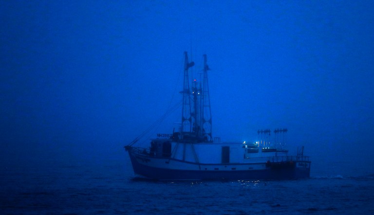 A crewman keeps watch near the cabin of a New Hampshire-based fishing boat as it motors cautiously through the dense fog into Portland Harbor early Wednesday, July 25, 2018, off South Portland, Maine. A tropical air mass will continue to bring areas of fog and scattered thunderstorms to the region through Thursday.