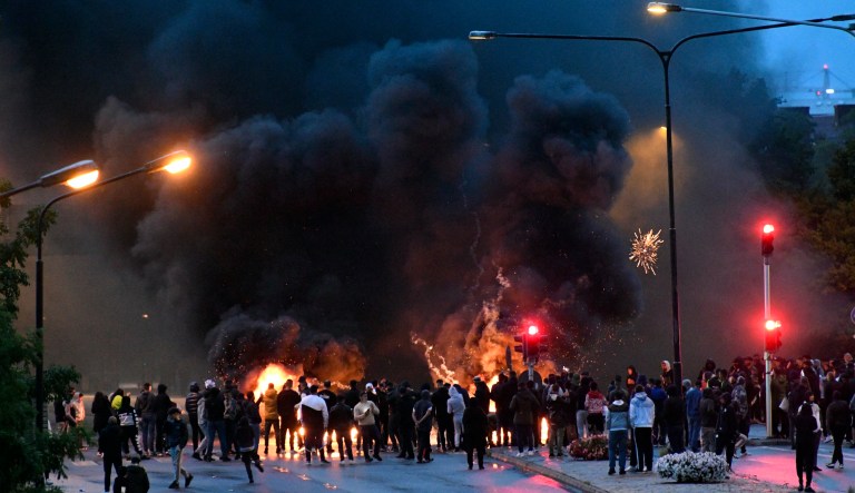 Smoke billows from burning tires and pallets and fireworks as a few hundred protesters riot in the Rosengard neighbourhood of Malmo, Sweden, on Aug. 28, 2020.