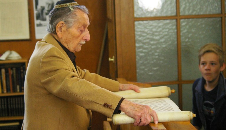Marko Feingold unrolls a scroll at a synagogue in Salzburg, Austria.