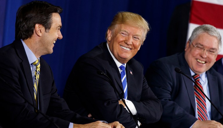 FILE - In this April 5, 2018, file photo, U.S. President Donald Trump smiles during a roundtable discussion on tax policy, in White Sulphur Springs, W.Va., with U.S. Rep. Evan Jenkins, R-W.Va., left, and West Virginia Attorney General Patrick Morrisey. Voters in the heart of Trump country are ready to decide the fate of West Virginia Republican Senate candidate Don Blankenship, a brash businessman and GOP outsider with a checkered past who is testing the success of President Donald Trumpâs playbook in one of the nationâs premiere Senate contests.