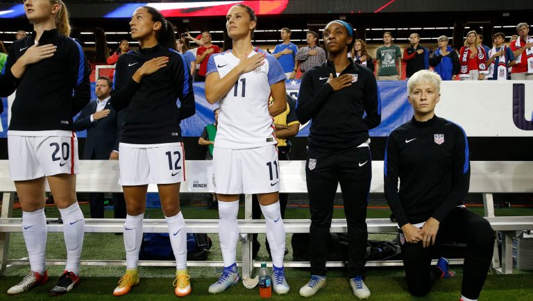 USA's Megan Rapinoe, right, kneels next to teammates Samanth Mewis (20) Christen Press (12), Ali Krieger (11), Crystal Dunn (16) and Ashlyn Harris (22) as the US national anthem is played before an exhibition soccer match against Netherlands Sunday, Sept. 18, 2016, in Atlanta. 