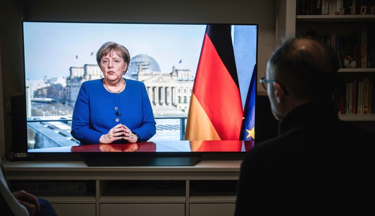 18 March 2020, North Rhine-Westphalia, Oberhausen: People watch the TV speech of the German Chancellor Angela Merkel (CDU) in a living room in Oberhausen. The Chancellor is talking about the coronavirus pandemic.