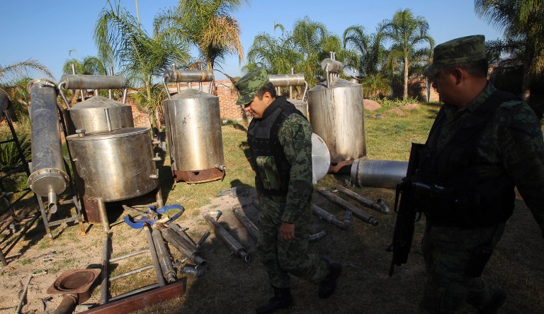 Soldiers walk past what was identified as "metal reactors" after a seizure of a large clandestine methamphetamine lab at a ranch in Tlajomulco de Zuniga, on the outskirts of Guadalajara, Mexico, Thursday, Feb. 9, 2012.