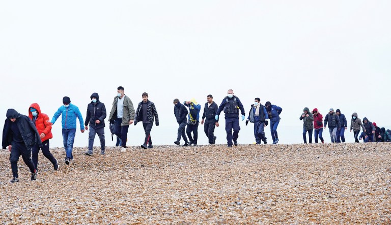 Migrants are led along a beach in Kent, England, after crossing from France on a dinghy, Nov. 21, 2021.