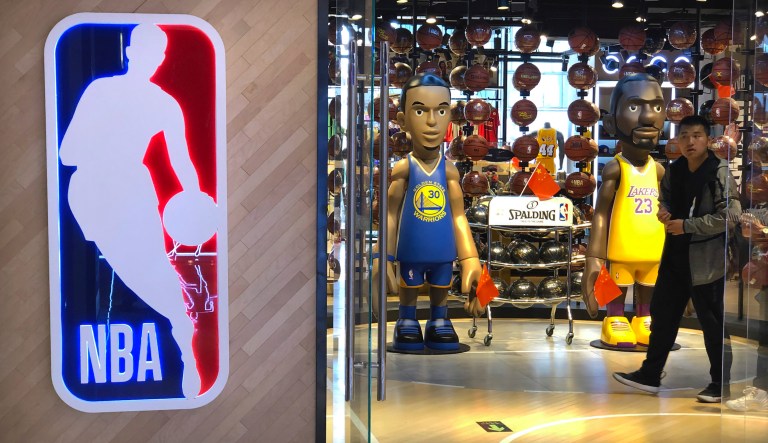 A man walks past statues of NBA players Stephen Curry of the Golden State Warriors, left, and Lebron James of the Los Angeles Lakers holding Chinese flags in the entrance of an NBA merchandise store in Beijing, Tuesday, Oct. 8, 2019. Chinese state broadcaster CCTV announced Tuesday it will no longer air two NBA preseason games set to be played in the country.