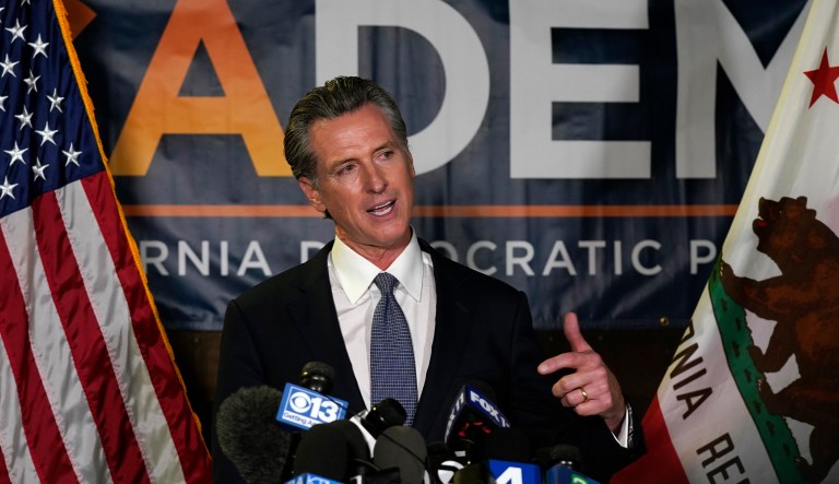 In this July 26, 2021 file photo Gov. Gavin Newsom holds a face mask while speaking at a news conference in Oakland, California. Conservative radio talk show host Larry Elder has emerged as the top contender for those who are looking to unseat Newsom in the Sept. 14 recall election. Elder, who is running to replace Newsom in the election, says he would erase state vaccine and mask mandates, is critical of gun control, opposes the minimum wage, and disputes the notion of systemic racism in America. 