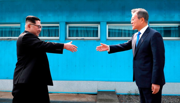 North Korean leader Kim Jong Un, left, prepares to shake hands with South Korean President Moon Jae-in over the military demarcation line at the border village of Panmunjom in Demilitarized Zone Friday, April 27, 2018. Their discussions will be expected to focus on whether the North can be persuaded to give up its nuclear bombs.