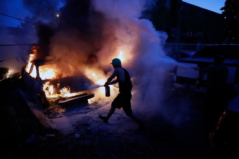 People attempt to extinguish cars on fire, Friday, May 29, 2020, in Minneapolis. Protests continued following the death of George Floyd, who died after being restrained by Minneapolis police officers on Memorial Day. 