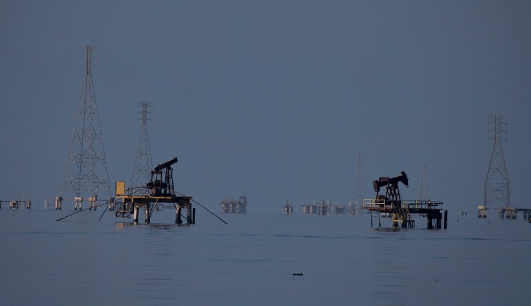 In this Aug. 20, 2018 photo, power lines stand alongside oil pumps on Maracaibo Lake, off Maracaibo, Venezuela.