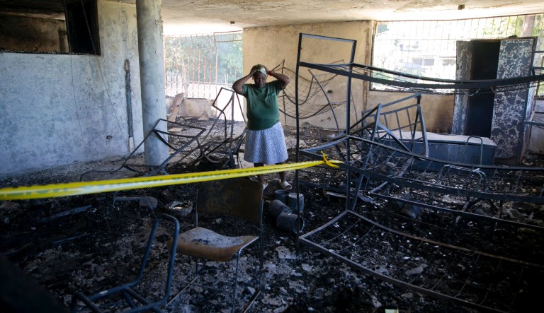 A staff worker gestures as she watching the burning body of a children inside of the Orphanage of the Church of Bible Understanding where a fire broke out the previous night in the Kenscoff area outside Port-au-Prince, Haiti, Friday, Feb. 14, 2020. A fire swept through this orphanage run by a Pennsylvania-based nonprofit group, killing 13 children, according to health care workers. 