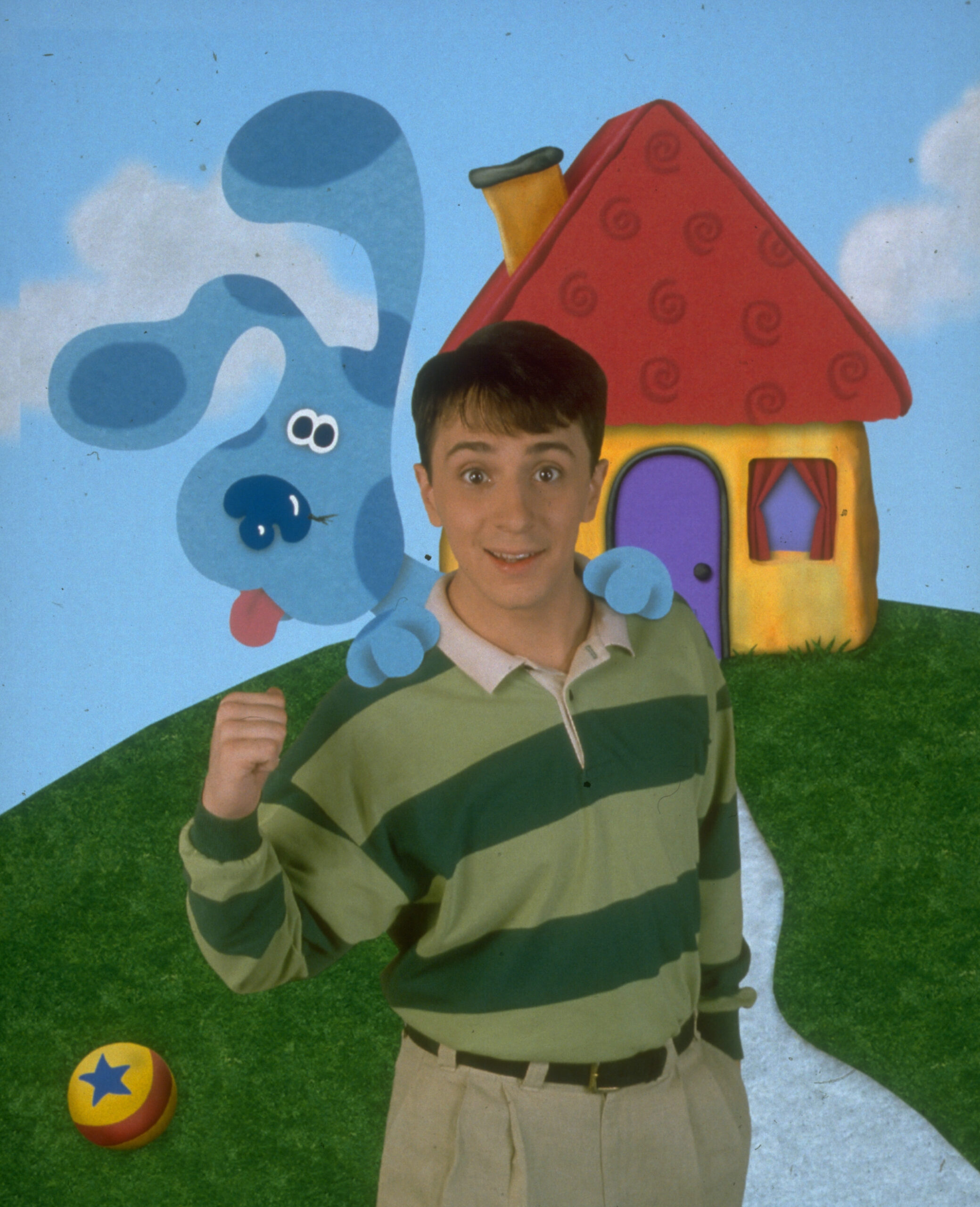 Steve Burns, the main actor in Blue's Clues, is seen with his dog Blue near a house on top of a hill.