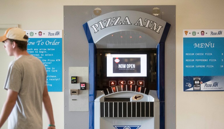 A student passes by a Pizza ATM machine at Xavier University, Friday, Sept. 9, 2016, in Cincinnati. The university partnered with French company Paline to install the first Pizza ATM in North America. The machine holds 70 pizzas at once as customers will be able to use a touch screen to pick one of the $10 pizzas, which will be heated for several minutes, placed in a cardboard box and ejected through a slot.