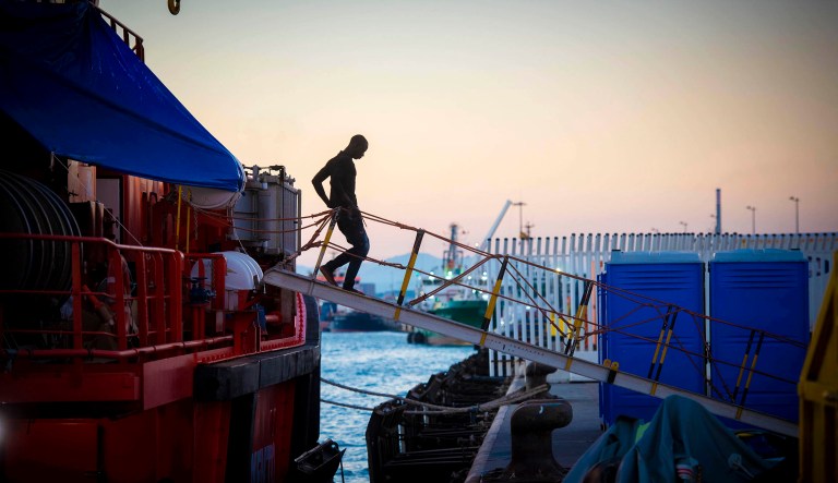 In this photo taken late Wednesday, July 25, 2018, a migrant goes ashore as he spends the night with others onboard a Spanish Maritime Rescue Service boat docked at the port of Algeciras, southern Spain, after being rescued in the Strait of Gibraltar.