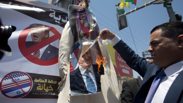 A Palestinian man burns a photo of the US President Donald Trump and King Hamad al-Khalifa of Bahrain during a protest against the American-led Mideast peace conference in the village of Halhul near the West Bank city of Hebron, Monday, June 24, 2019. Hundreds of Palestinians are protesting throughout the West Bank against this week's economic conference in Bahrain that will kick off the Trump administration's plan for Mideast peace. 