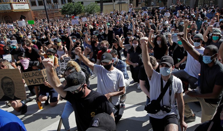 People raise a fist as they take a knee during a protest Tuesday, June 2, 2020, in Redwood City, Calif. 