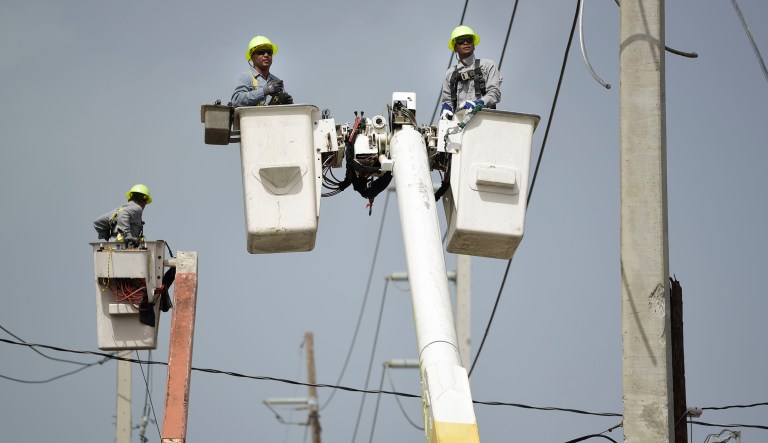 In this Thursday, Oct. 19, 2017 photo, a brigade from the Electric Power Authority repairs distribution lines damaged by Hurricane Maria in the Cantera community of San Juan, Puerto Rico. The storm struck after the Authority had filed for bankruptcy in July, put off maintenance and had finished dealing with outages from Hurricane Irma.