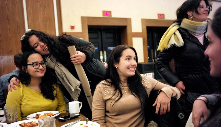 In this Tuesday, Jan. 30, 2018 photo, Brown University students from Puerto Rico, Jessica Ortiz, of Gurabo, seated left, receives a hug from Mariana Ramos Ortiz, of Cabo Rojo, top left, as Fabiola Guasp, of San Juan, center, speaks with Coral Murphy, of Manati, right, and Katerina Ramos Jordan, of Trajillo Alto, top right, following dinner in a cafeteria on the school's campus, in Providence, R.I.