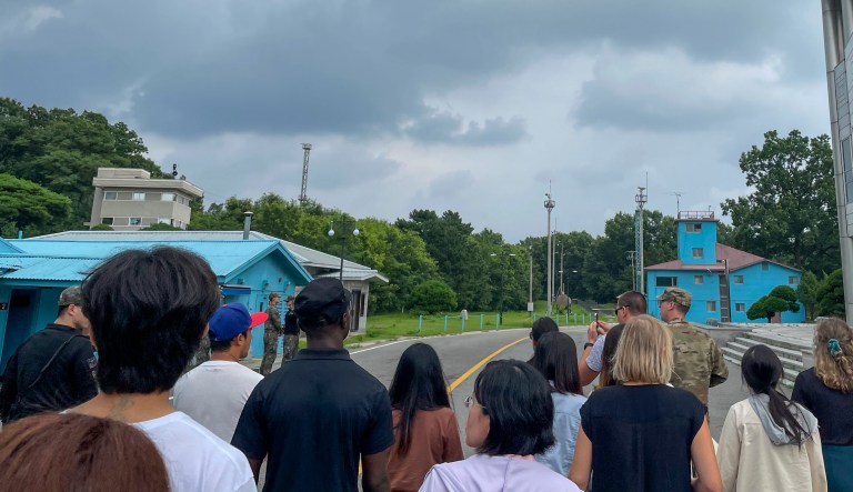A group of tourists stand near a border station at Panmunjom in the Demilitarized Zone in Paju, South Korea, Tuesday, July 18, 2023. Not long after this photo was taken, Travis King, a U.S. soldier, pictured with a dark blue shirt and dark cap, fourth left, bolted across the border and became the first known American detained in the North in nearly five years. 