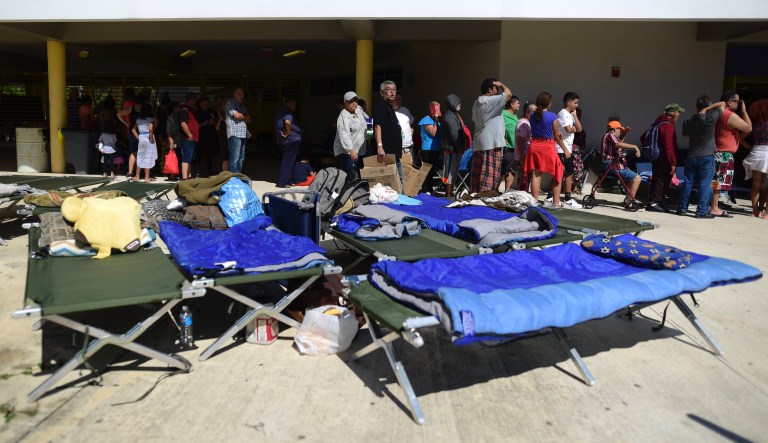People whose homes are unsafe to enter after the previous day's magnitude 6.4 earthquake line up for lunch in an outdoor area of the Bernardino Cordero Bernard High School, amid aftershocks and no electricity in Ponce, Puerto Rico, Wednesday, Jan. 8, 2020. More than 250,000 Puerto Ricans remained without water on Wednesday and another half a million without power, which also affected telecommunications.