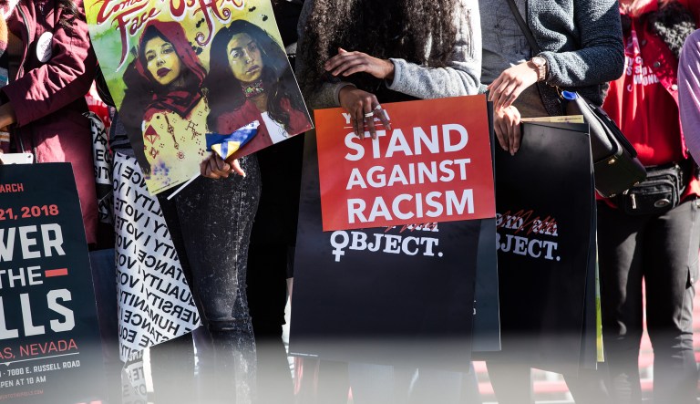 An attendee holds a sign reading "Stand Against Racism" during the Women's March One-Year Anniversary: Power To The Polls event in Las Vegas, Nevada, U.S., on Sunday, Jan. 21, 2018. On the anniversary of the Women's March, the Power to the Polls rally aims at a tighter objective, to launch a national voter registration and mobilization tour with a goal to elect more women and progressive candidates to public office.