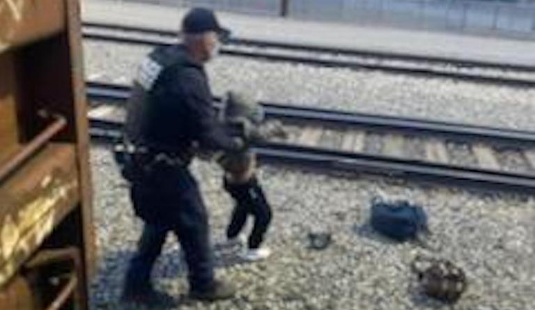 A Customs and Border Protection officer with a child who had been riding aboard a freight train passing from Mexico into the U.S.