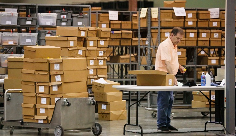 An employees at the Palm Beach County Supervisor of Elections office feed ballots through a machine as he count votes during a recount on Wednesday, Nov. 14, 2018, in West Palm Beach, Fla.