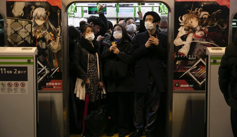 Commuters wearing masks stand in a packed train at Shinagawa Station in Tokyo, Monday, March 2, 2020. 