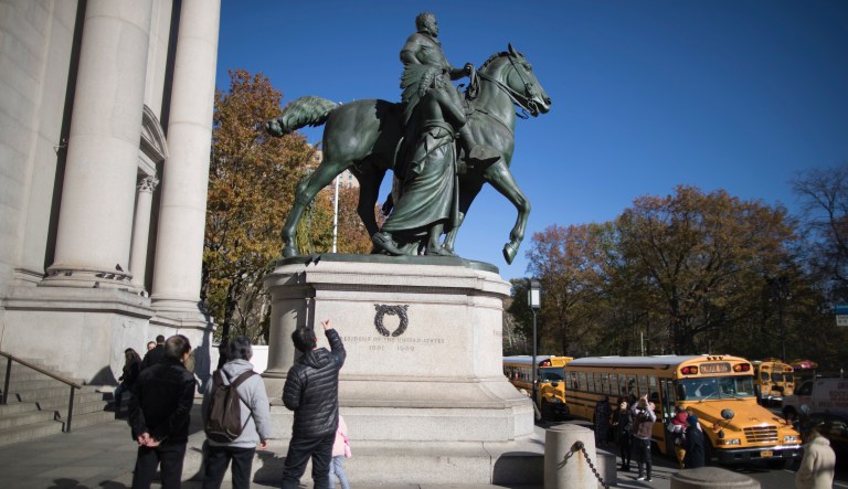 Visitors to the American Museum of Natural History look at a statue of Theodore Roosevelt. 