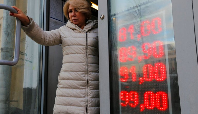 In this Feb. 24, 2022, photo, a woman leaves an exchange office with screen showing the currency exchange rates of U.S. Dollar and Euro to Russian Rubles in Moscow, Russia. The harsh sanctions imposed on Russia and the resulting crash of the ruble have the Kremlin scrambling to keep the country's economy running. For Russian President Vladimir Putin, that means finding workarounds to the economic blockade even as his forces continue to invade Ukraine.