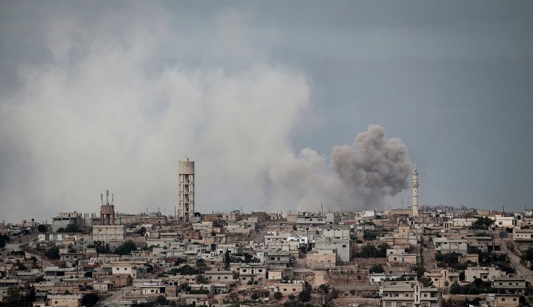 In this Sept. 19, 2013, file photo, smoke rises after a TNT bomb was thrown from a helicopter, hitting a rebel position during heavy fighting between troops loyal to president Bashar Assad and opposition fighters, in a neighbouring village to Kafr Nabuda, in the Idlib province countryside, Syria.
