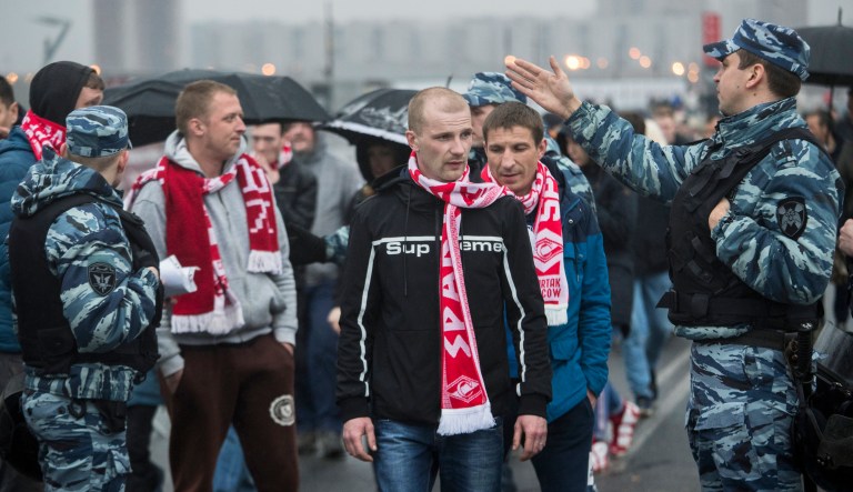 In this photo taken on Wednesday, April 18, 2018, police officers stop to check Spartak Moscow's supporters before the a Russian Premier League Championship soccer match between Spartak Moscow and Tosno in Moscow, Russia. Ahead of the World Cup, Russian authorities are cracking down on the hooligan culture in football. Groups which wreaked havoc two years ago report surveillance and threats from law enforcement.