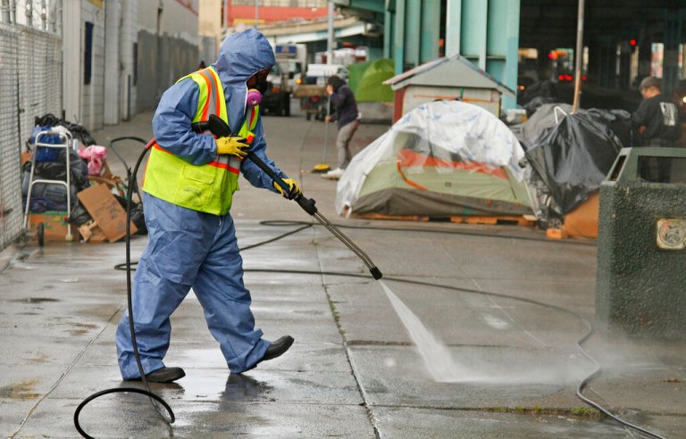 A city worker uses a power washer to clean the sidewalk by a tent city along Division Street Friday, Feb. 26, 2016, in San Francisco. 