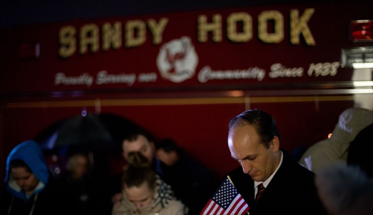 Mourners listen to a memorial service over a loudspeaker outside Newtown High School for the victims of the Sandy Hook Elementary School shooting, Sunday, Dec. 16, 2012, in Newtown, Conn.