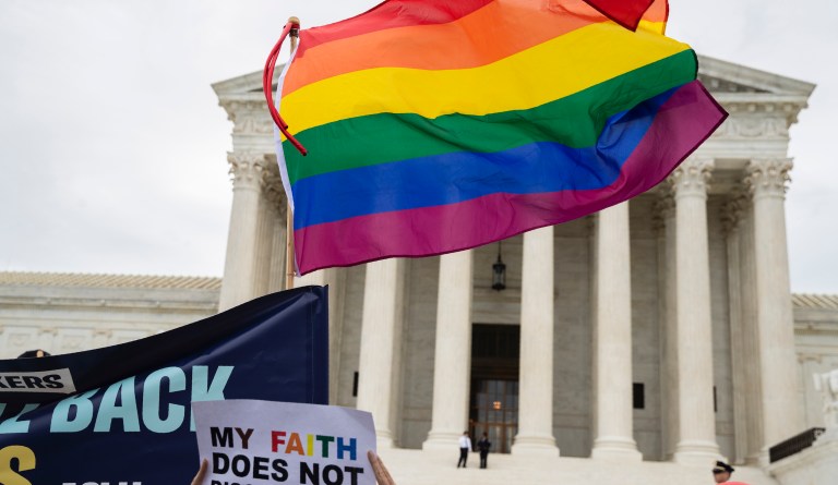 Supporters of the LGBT wave their flag in front of the U.S. Supreme Court, Tuesday, Oct. 8, 2019, in Washington.  The Supreme Court is set to hear arguments in its first cases on LGBT rights since the retirement of Justice Anthony Kennedy. Kennedy was a voice for gay rights while his successor, Brett Kavanaugh, is regarded as more conservative.