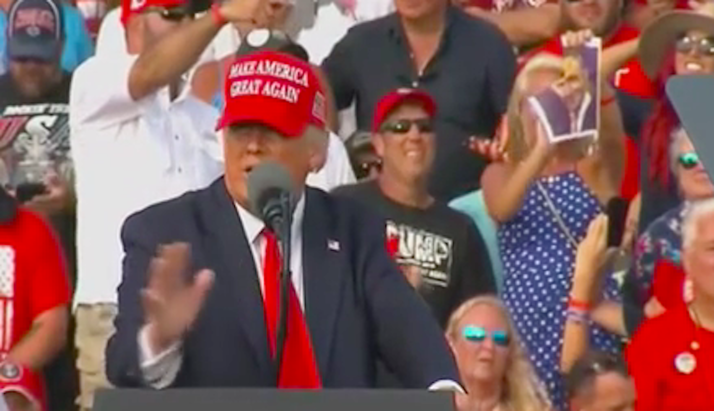 Trump rally attendee seated behind president tears up photos of Pelosi and Schumer