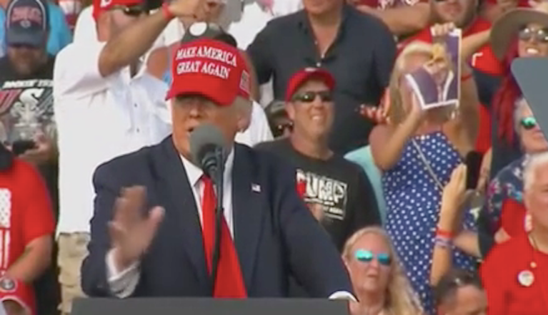 Trump rally attendee seated behind president tears up photos of Pelosi and Schumer