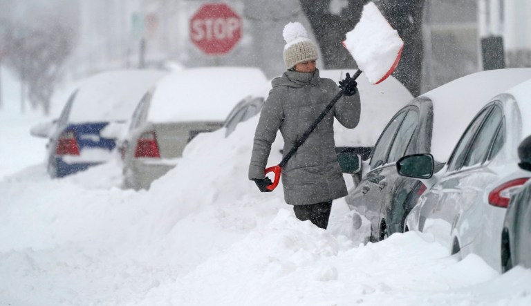 A woman tosses a shovel full of snow while digging out her car, Thursday morning, Dec. 17, 2020, in Manchester, N.H. Southern New Hampshire is expected to be covered with over a foot of snow through the day from a Winter storm.