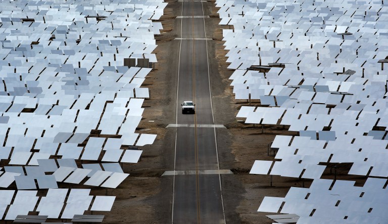 In this Aug. 13, 2014 photo, A truck drives through an array of mirrors at the Ivanpah Solar Electric Generating System near Primm, Nev. The site uses over 300,000 mirrors to focus sunlight on boilers' tubes atop 450 foot towers heating water into steam which in turn drives turbines to create electricity.