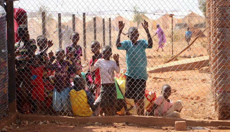 In this Feb. 20, 2018, photo, newly arrived Sudanese refugees wait behind a wire fence at a reception center in Yida, South Sudan. While millions of South Sudanese flee their country in what the United Nations has called the world's fastest-growing refugee crisis since the Rwandan genocide, hundreds of thousands of people from neighboring Sudan have found an unlikely haven there from fighting at home.