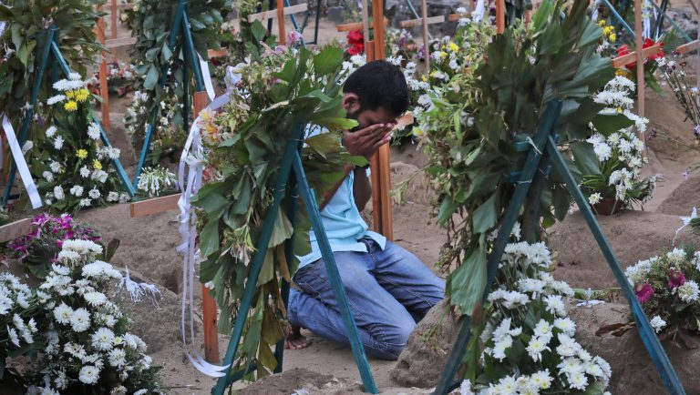 A Sri Lankan relative of a victim of Easter Sunday bomb blasts pays tribute at the burial site after a televised Sunday mass by Sri Lankan Archbishop Cardinal Malcolm Ranjith, in Negombo, north of Colombo, Sri Lanka, Sunday, April 28, 2019. Sri Lanka's Catholics celebrated Sunday Mass in their homes by a televised broadcast as churches across the island nation shut over fears of militant attacks, a week after the Islamic State-claimed Easter suicide bombings killed over 250 people.
