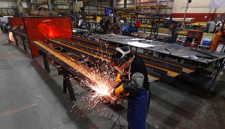 In this Thursday, Jan. 23, 2014 photo, Jesus Rodriguez grinds steel at the IDEAL Group in Detroit. 