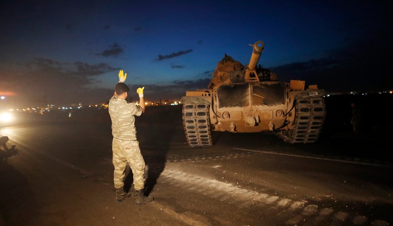 A Turkish army officer guides a comrade driving a tank to its new position, after was uploaded from a truck, on the Turkish side of the border between Turkey and Syria, in Sanliurfa province, southeastern Turkey, Tuesday, Oct. 8, 2019.
