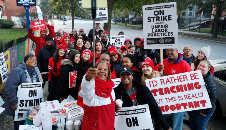 Striking teachers and support staff pose for a group shot outside the John J. Pershing Magnet School on the first day of their strike in the city's Bronzeville neighborhood Thursday, Oct. 17, 2019, in Chicago. Chicago teachers went on strike Thursday, marching on picket lines after failing to reach a contract deal with the nation's third-largest school district in a dispute that canceled classes for more than 300,000 students.