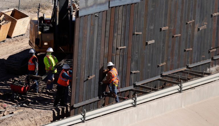 In this Tuesday, Jan. 22, 2019, photo, workers place sections of metal wall as a new barrier is built along the Texas-Mexico border near downtown El Paso. 