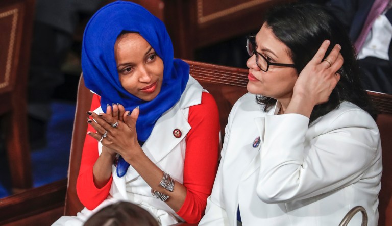 In this Feb. 5, 2019, photo, Rep. Ilhan Omar, D-Minn., left, joined at right by Rep. Rashida Tlaib, D-Mich., listens to President Donald Trump's State of the Union speech, at the Capitol in Washington. A tweet by Omar has sparked a bipartisan backlash, with some accusing her of being anti-Semitic.