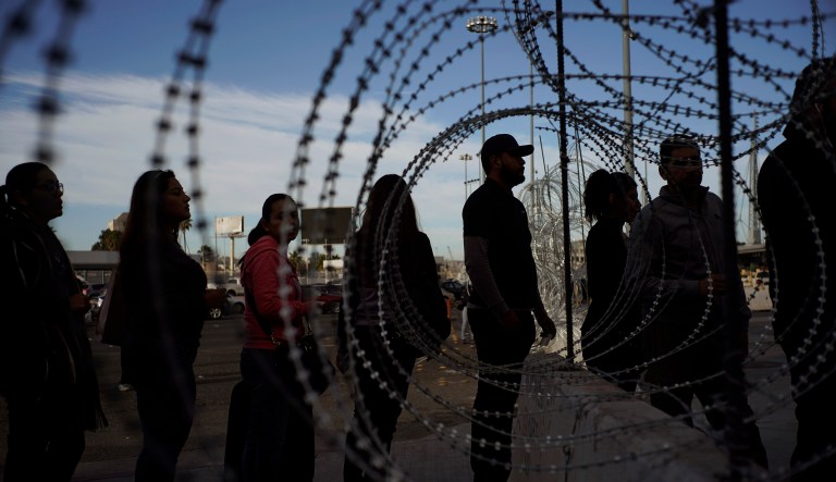 Pedestrians stand near barbed wire at a legal Mexico-U.S. border crossing as they prepare to leave Tijuana, Mexico, Monday, Nov. 19, 2018.