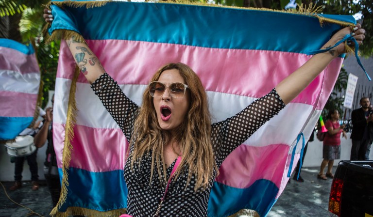 Lola Vazquez, who identifies as transgender, waves a transgender flag during a protest against a deal Guatemalan President Jimmy Morales' government signed with Washington that would force Salvadoran and Honduran migrants to request asylum in Guatemala instead of the United States, in Guatemala City, Wednesday, July 31, 2019. Critics of the deal point out that Guatemala has the same problems that are driving Hondurans and Salvadorans to flee their homes: violence, poverty, joblessness and a prolonged drought that has severely hurt farmers. 