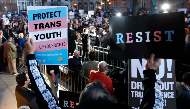 A participant holds signs from a stoop next door to the Stonewall National Monument during a rally in support of transgender youth, Thursday, Feb. 23, 2017, in New York.