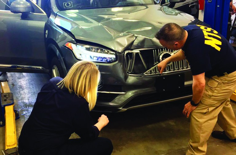 FILE- In this March 20, 2018, file photo provided by the National Transportation Safety Board, investigators examine a driverless Uber SUV that fatally struck a woman in Tempe, Ariz. Uber announced Wednesday, May 23, that it is pulling its self-driving cars out of Arizona, a reversal triggered by the recent death of woman who was run over by one of the ride-hailing service's robotic vehicles while crossing a darkened street in a Phoenix suburb. (National Transportation Safety Board via AP, File)