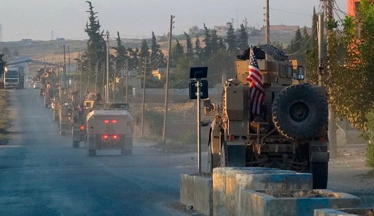 In this image provided by Hawar News Agency, ANHA, U.S. military vehicles travel down a main road in northeast Syria, Monday, Oct. 7, 2019. U.S.-backed Kurdish-led forces in Syria said American troops began withdrawing Monday from their positions along Turkey's border in northeastern Syria, ahead of an anticipated Turkish invasion that the Kurds say will overturn five years of achievements in the battle against the Islamic State group.